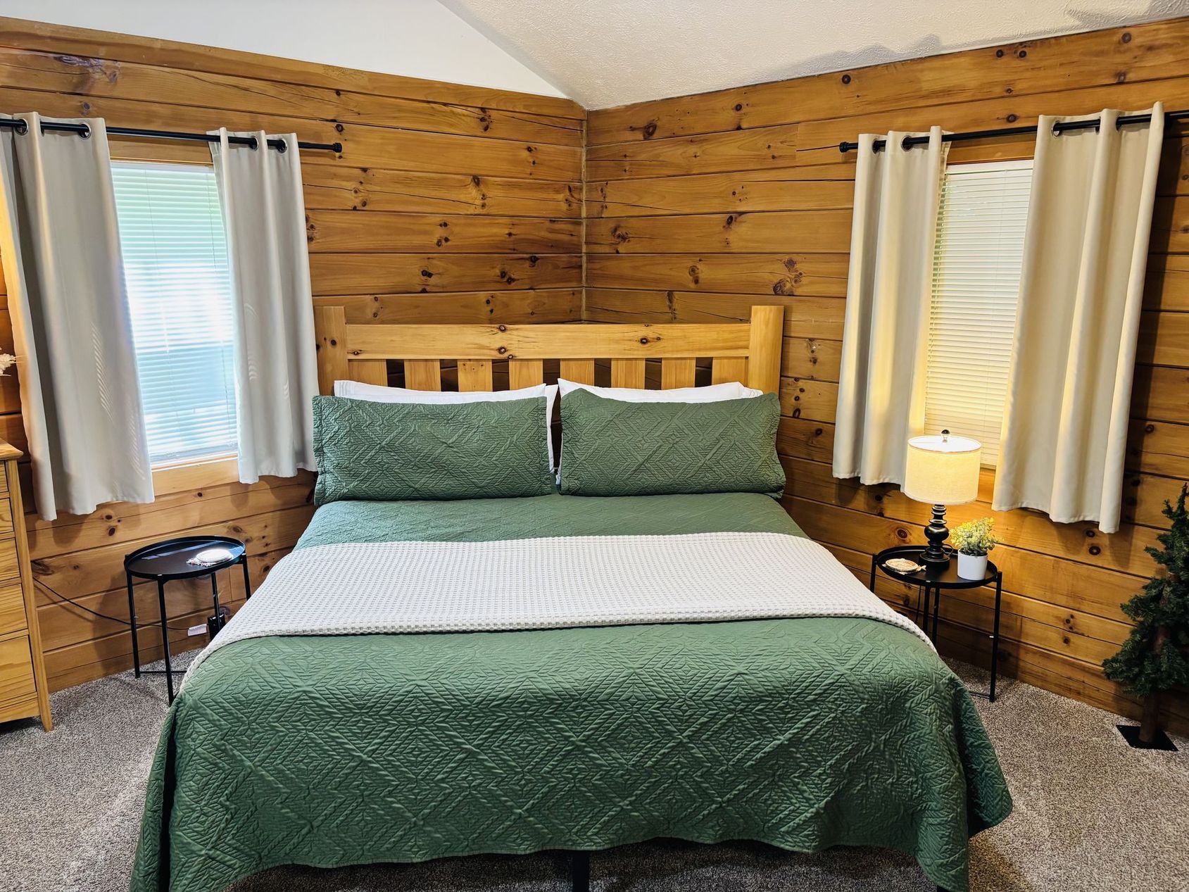 King bed with a green quilt against knotty pine walls at Aspen Cabin