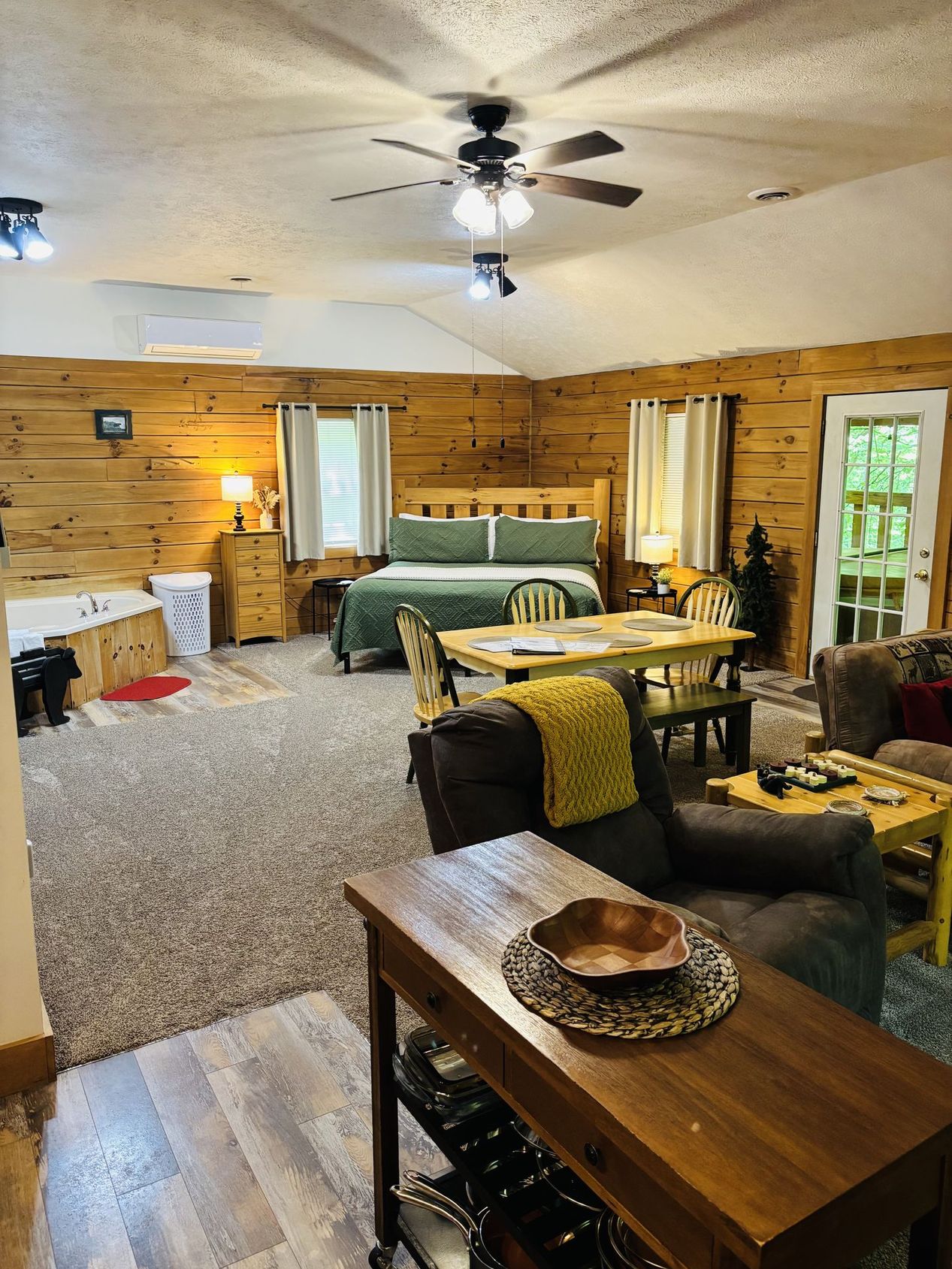 The whole of Aspen Cabin from the front door — king bed, corner jacuzzi, dining table and sitting area in one open room