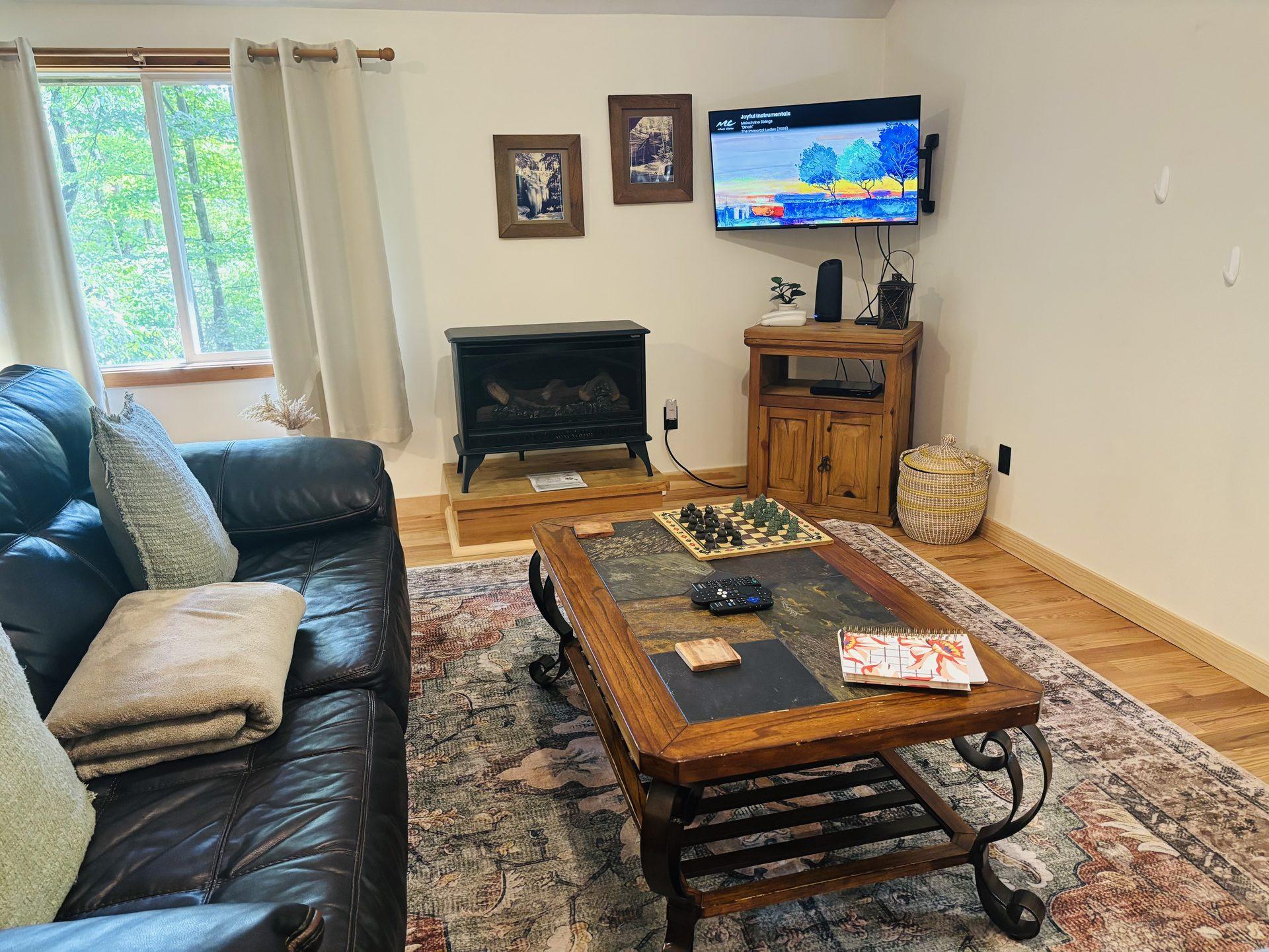 Gas fireplace, television and a games table in the sitting area at Sugar Maple Cabin