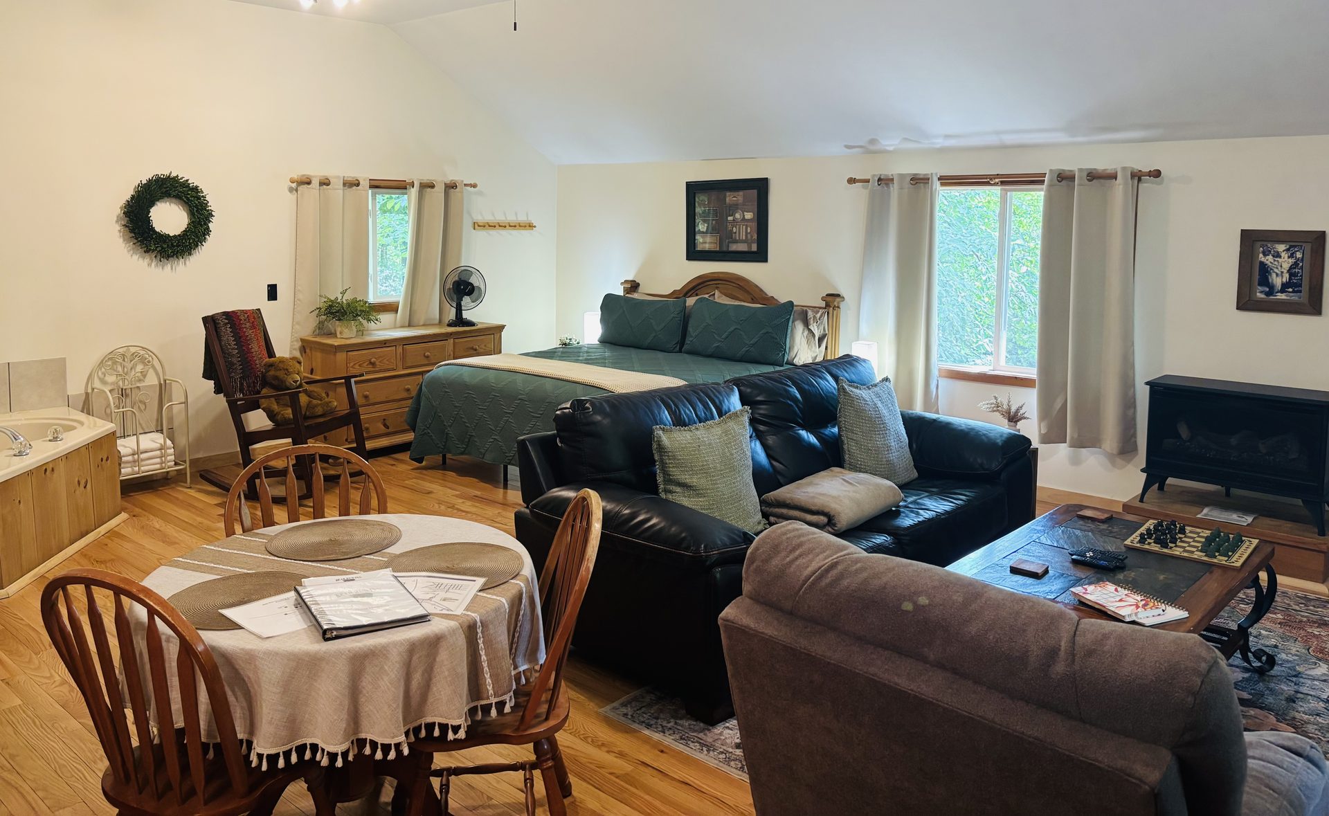 The open great room at Sugar Maple Cabin — king bed, sofa, dining table and corner jacuzzi tub in one space