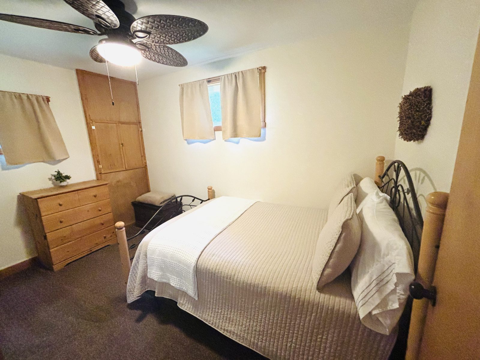 A bedroom at Red Oak Cabin with white bedding, a log-post bed and a pine dresser