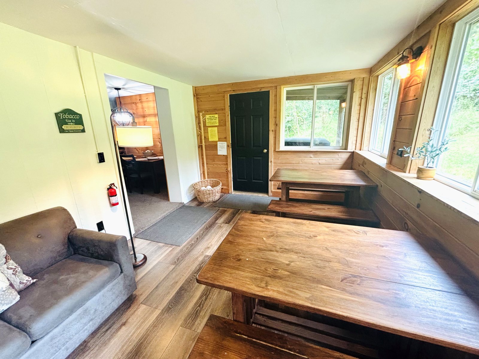 Two long farmhouse tables and benches in the sun room at Red Oak Cabin, windows on three sides