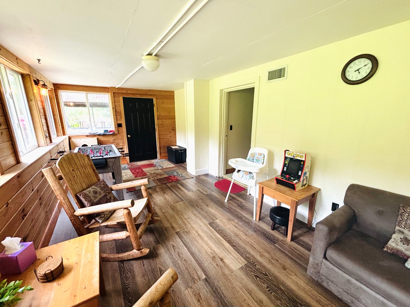 The sun room at Red Oak Cabin, with a foosball table, rocking chairs and a sofa