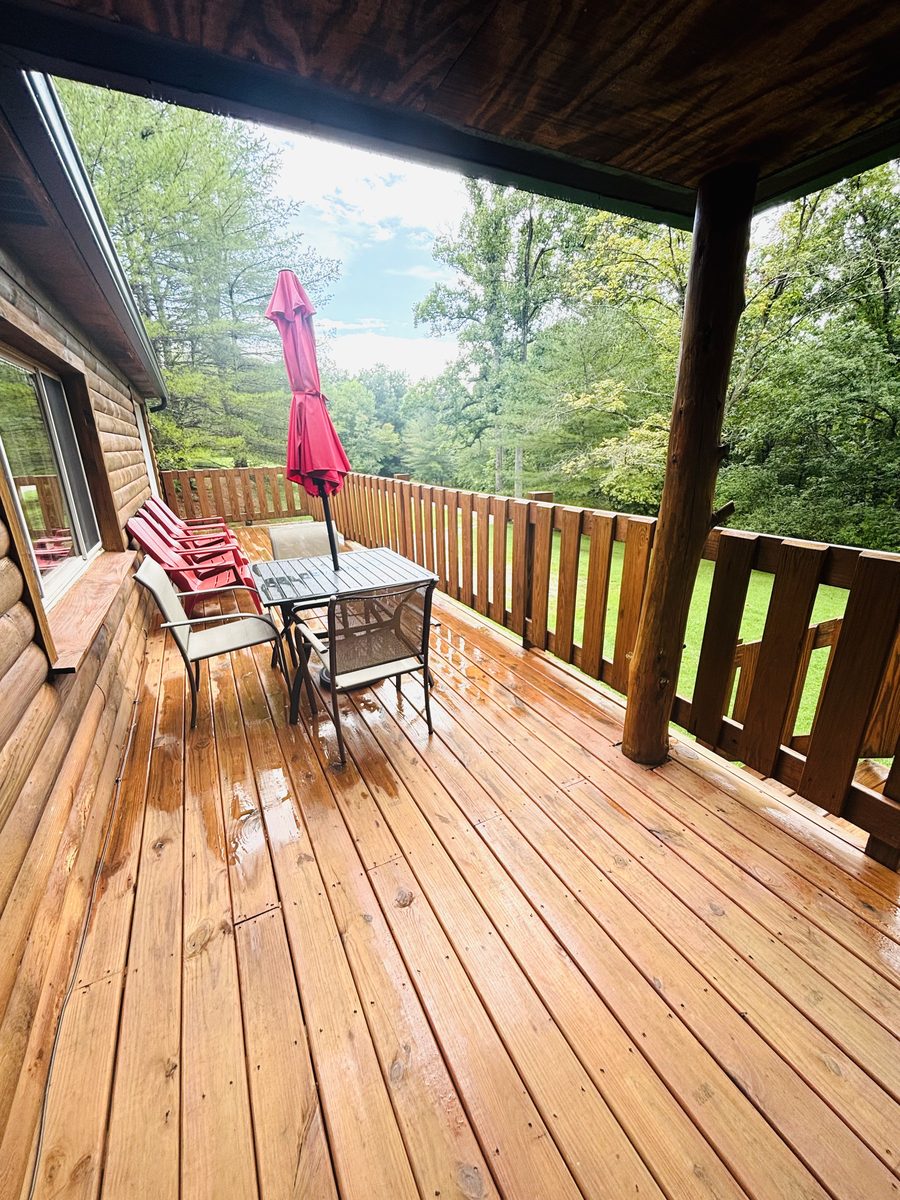 Deck chairs and the umbrella table at Red Oak Cabin, with the lawn falling away below