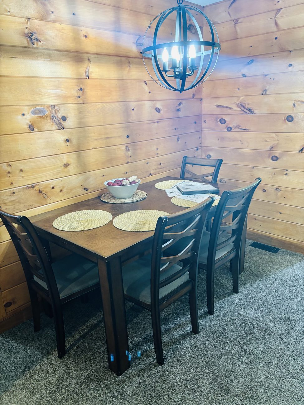 The dining table at Red Oak Cabin, set for six under a globe light against a pine wall