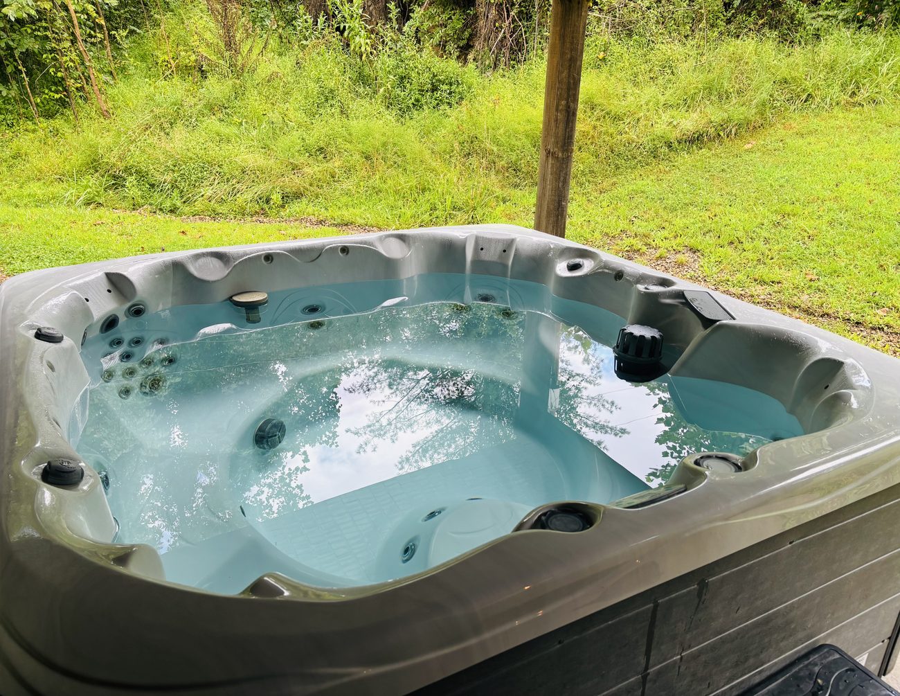 The hot tub at Red Oak Cabin, clear water and the green bank behind
