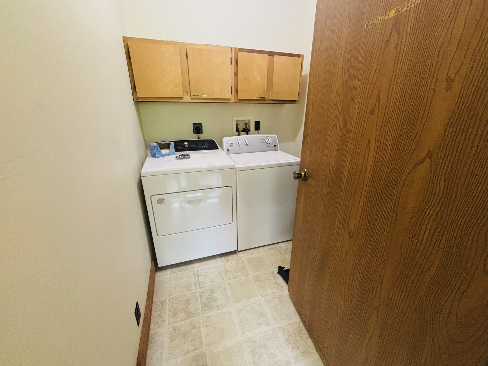 The laundry room at Red Oak Cabin, with a full-size washer and dryer and cupboards above
