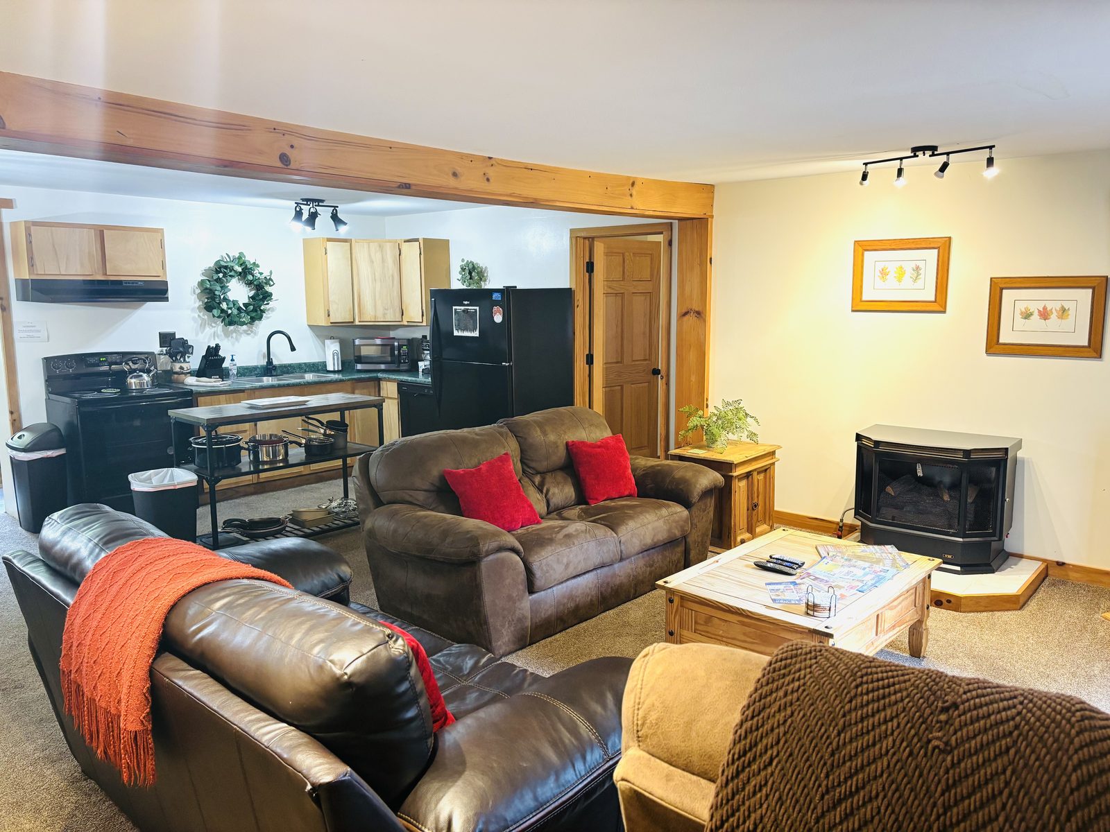 The living room at Red Oak Cabin looking through to the kitchen, with a wood stove and seating for a crowd