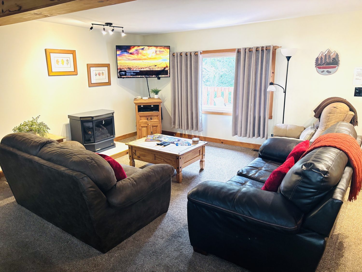 Sofas and a wood stove in the living room at Red Oak Cabin, with the television above