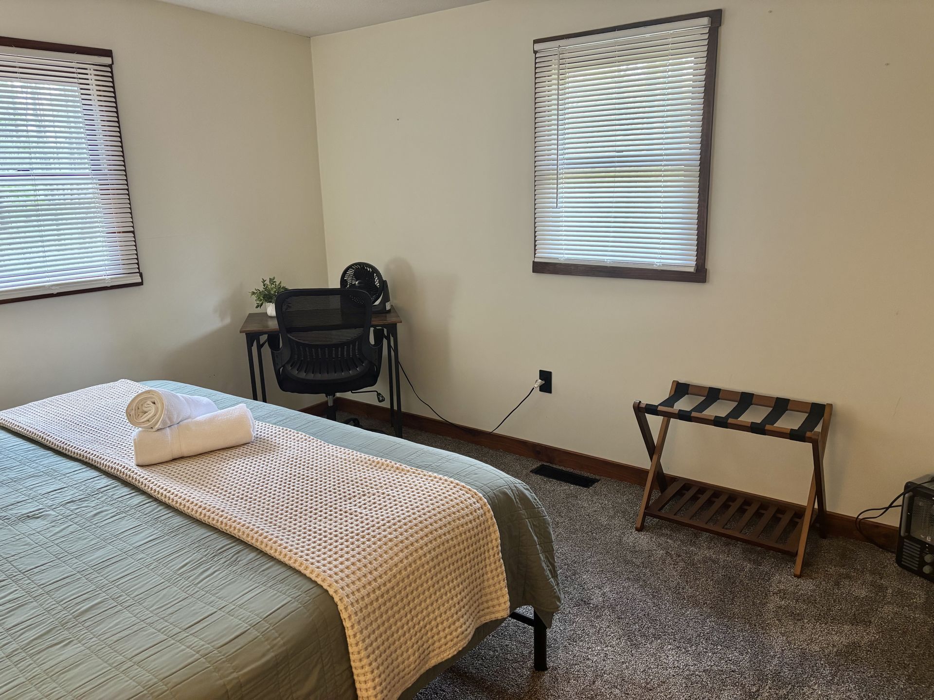 A downstairs bedroom at Redbud Cabin with a desk, luggage rack and two windows