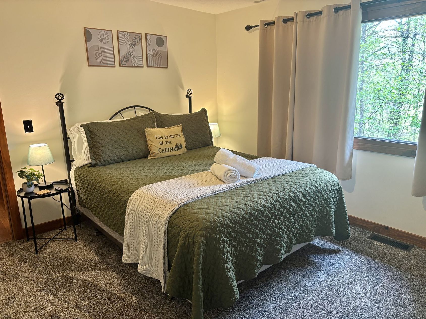 A downstairs bedroom at Redbud Cabin, green quilt and reading lamps either side