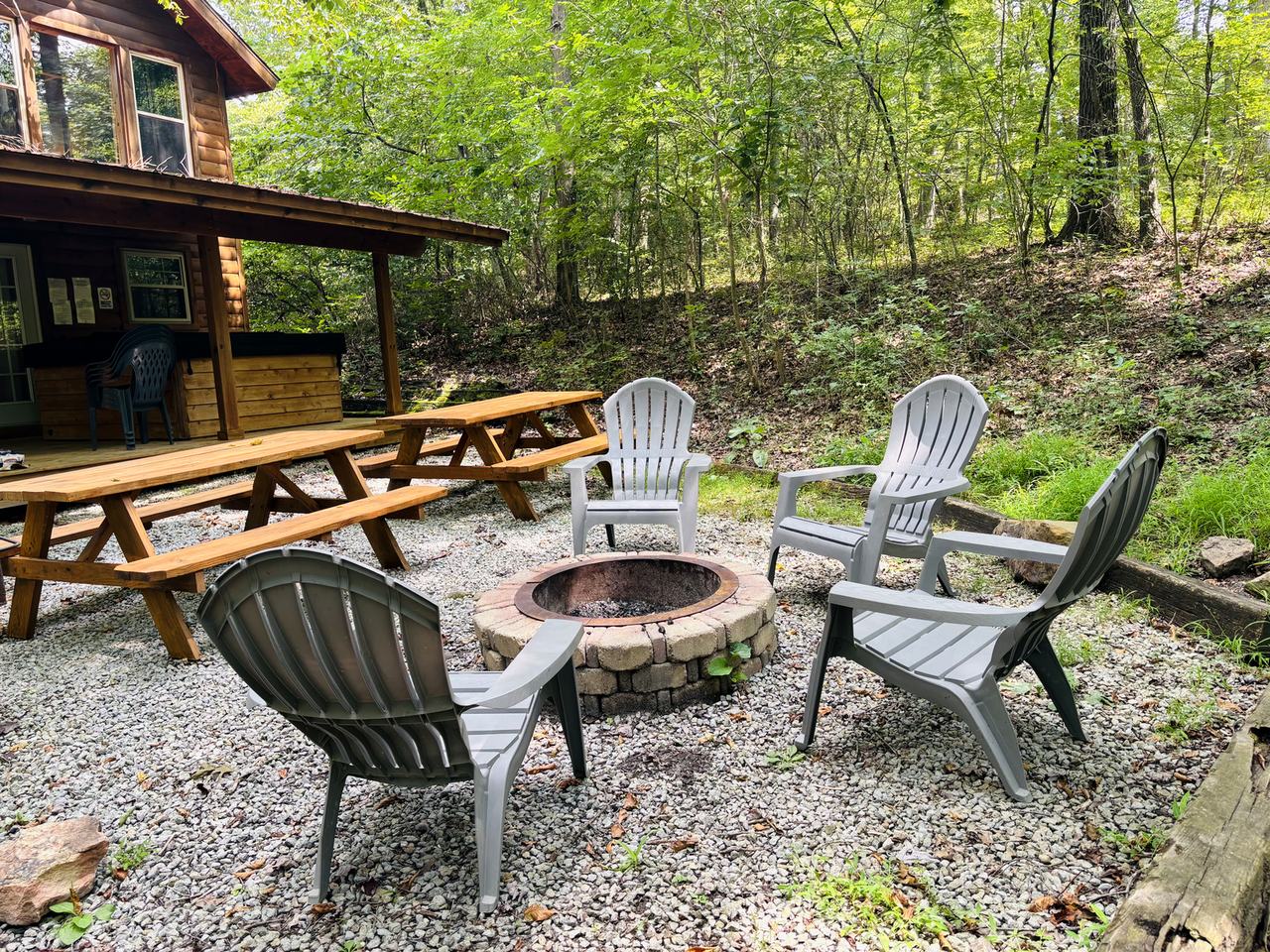 The fire ring and picnic tables behind Redbud Cabin, with the covered back deck beyond