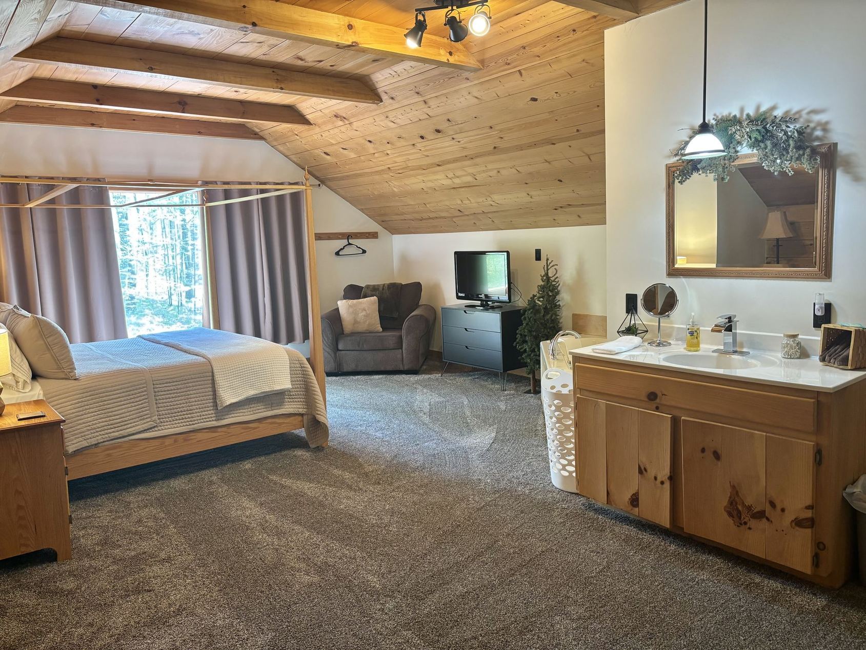The loft master bedroom at Redbud Cabin, with vanity and seating under a pine ceiling