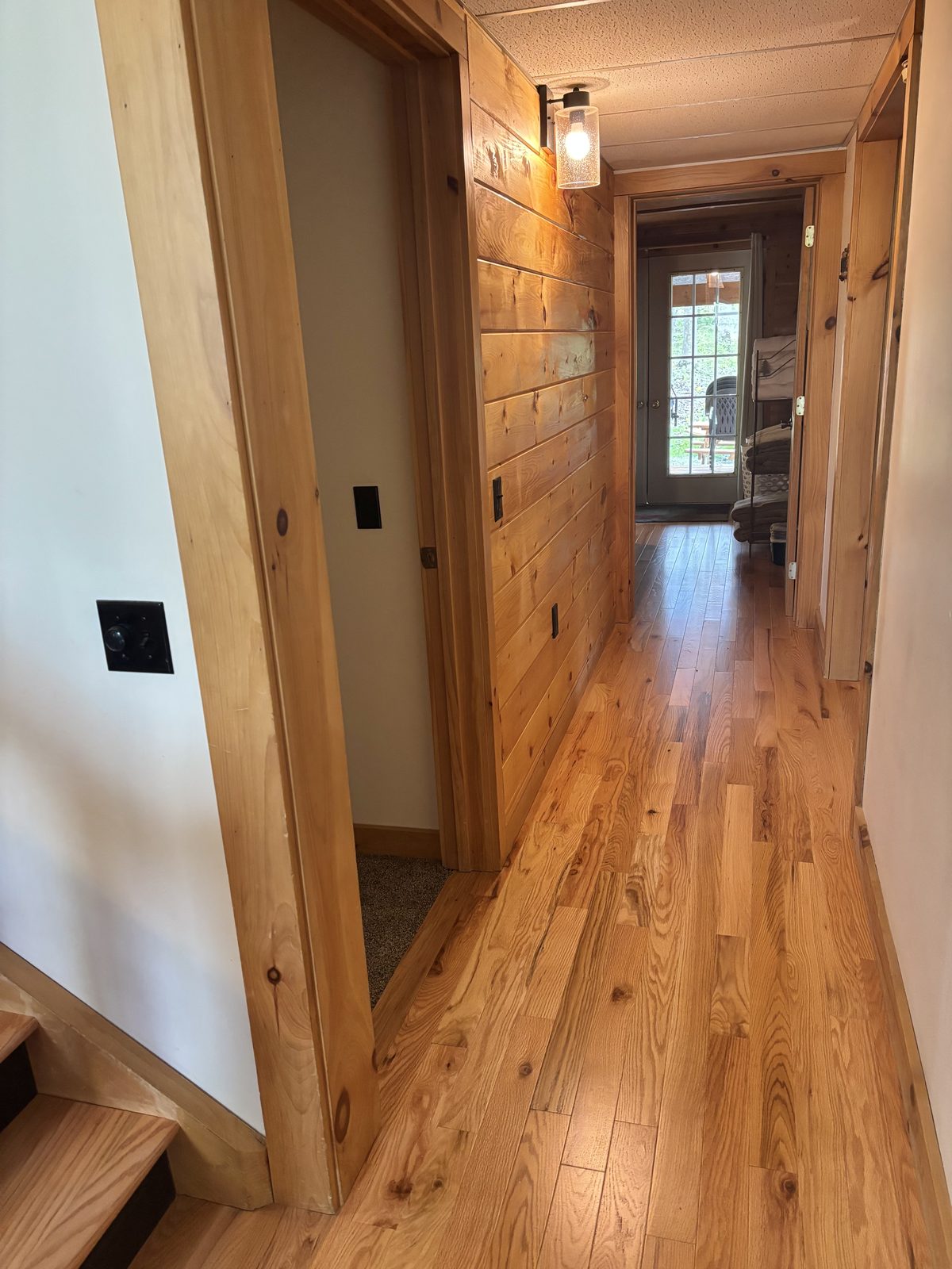 The hallway at Redbud Cabin, hickory floors and pine walls running past the downstairs bedrooms to the back door
